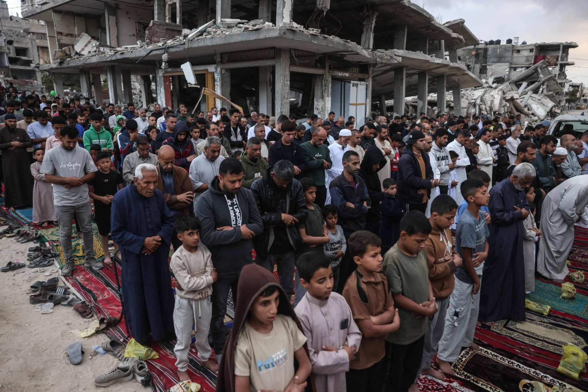 TOPSHOT - Palestinians perform morning prayers marking the start of Eid al-Adha, the Feast of Sacrifice, on a heavily damaged street in Khan Yunis, southern Gaza Strip, on May 27, 2026. Since October 10, a fragile US-sponsored truce in Gaza has largely halted the fighting between Israeli forces and Hamas, but both sides have alleged frequent violations. (Photo by BASHAR TALEB / AFP)